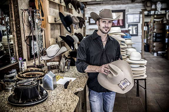 Jeff Biggar holding a hat in his hat shop