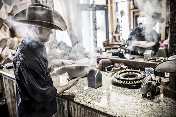 Jeff Biggar steaming and shapping a hat in his hat shop